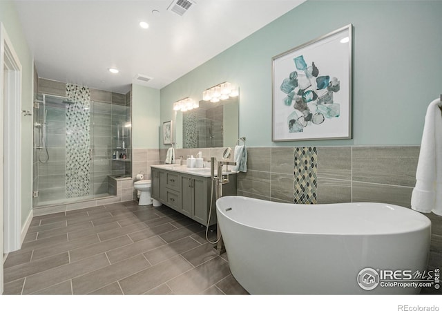 full bathroom with vanity, toilet, tile walls, and separate shower and tub