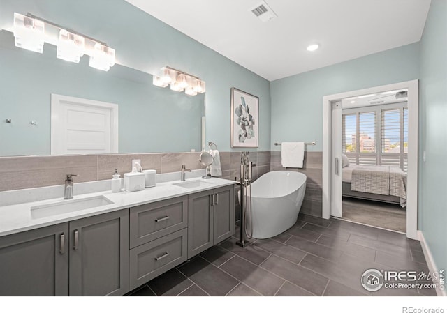 bathroom with a tub, tile patterned floors, backsplash, and vanity