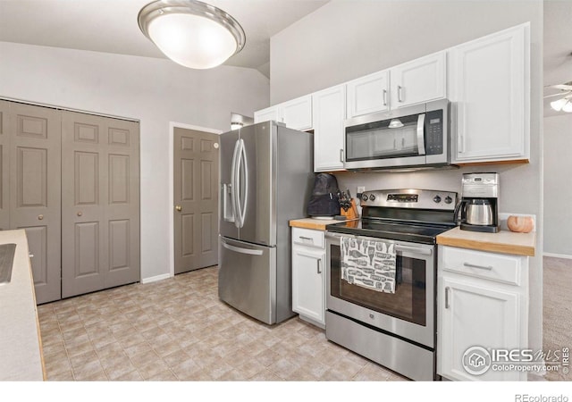 kitchen with stainless steel appliances, white cabinetry, and vaulted ceiling