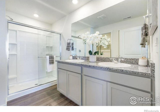 bathroom with a shower with shower door, wood-type flooring, and vanity