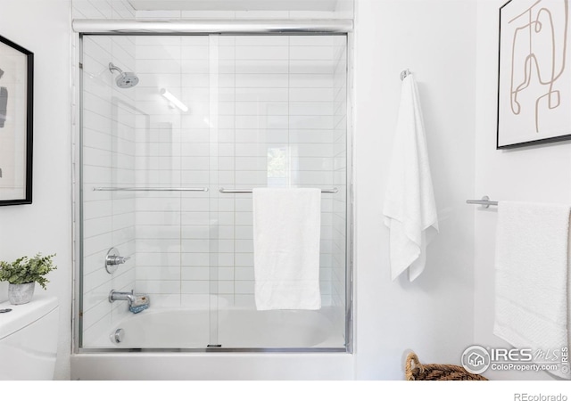 bathroom with bath / shower combo with glass door and toilet