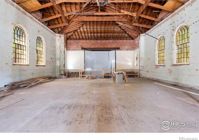 miscellaneous room featuring high vaulted ceiling and concrete flooring