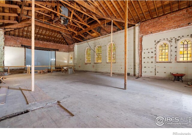 miscellaneous room with high vaulted ceiling and concrete flooring