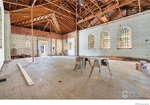 miscellaneous room featuring high vaulted ceiling and concrete floors