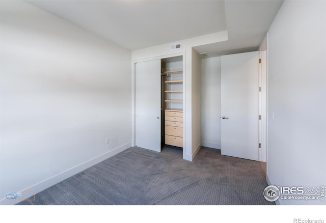 unfurnished bedroom with dark carpet and a closet