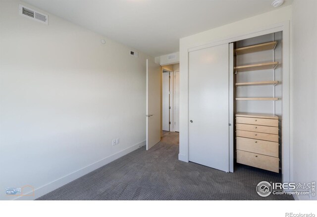 unfurnished bedroom featuring dark carpet and a closet