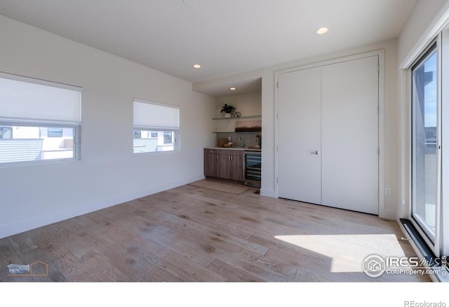 unfurnished bedroom featuring a closet, wine cooler, and light hardwood / wood-style flooring