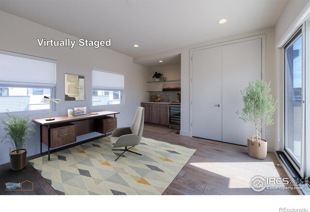 office space with light wood-type flooring, wine cooler, and sink