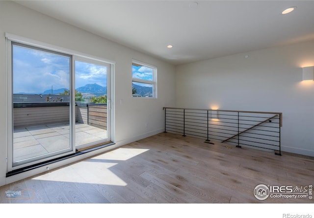 spare room with a mountain view and light hardwood / wood-style floors