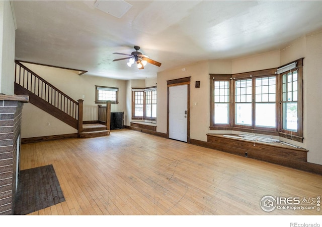 unfurnished living room featuring light hardwood / wood-style flooring, ceiling fan, and radiator heating unit