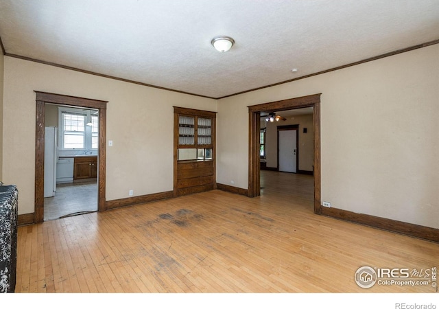 unfurnished room featuring a textured ceiling, ornamental molding, and wood-type flooring