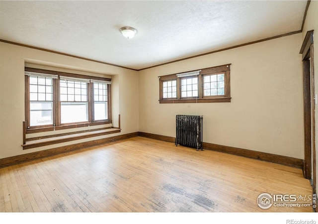 unfurnished room with a textured ceiling, radiator, crown molding, and light hardwood / wood-style flooring