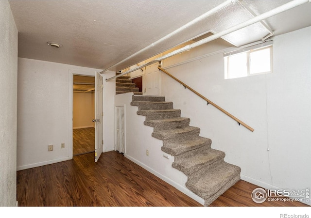 stairs with a textured ceiling and hardwood / wood-style floors