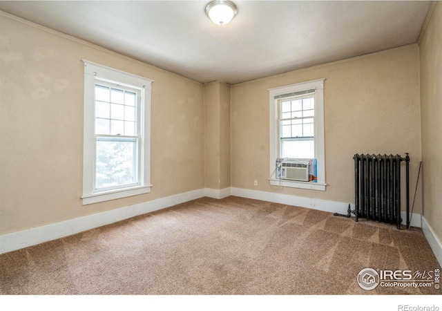 carpeted spare room featuring cooling unit, plenty of natural light, radiator heating unit, and ornamental molding