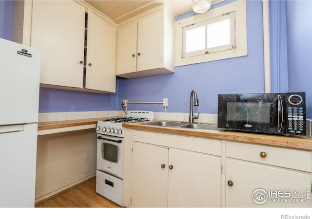 kitchen featuring light wood-type flooring, white appliances, sink, and white cabinets