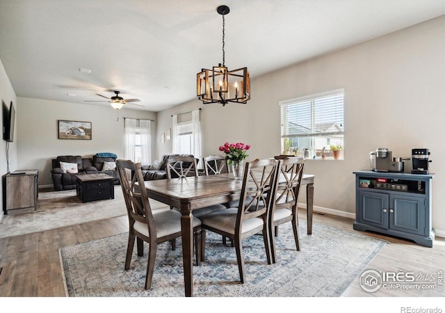 dining area with light hardwood / wood-style floors and ceiling fan with notable chandelier