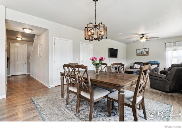 dining space with ceiling fan with notable chandelier and light hardwood / wood-style flooring