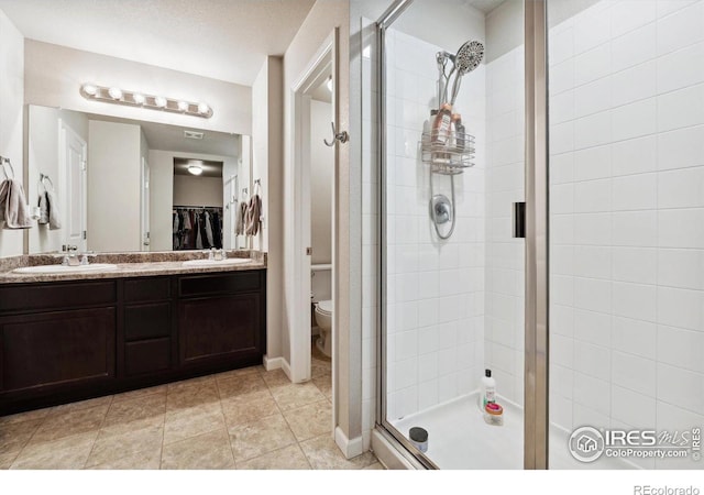 bathroom featuring a textured ceiling, a shower with door, vanity, and toilet