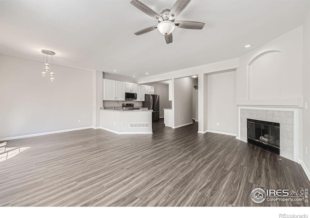 unfurnished living room featuring dark hardwood / wood-style flooring, ceiling fan, and sink