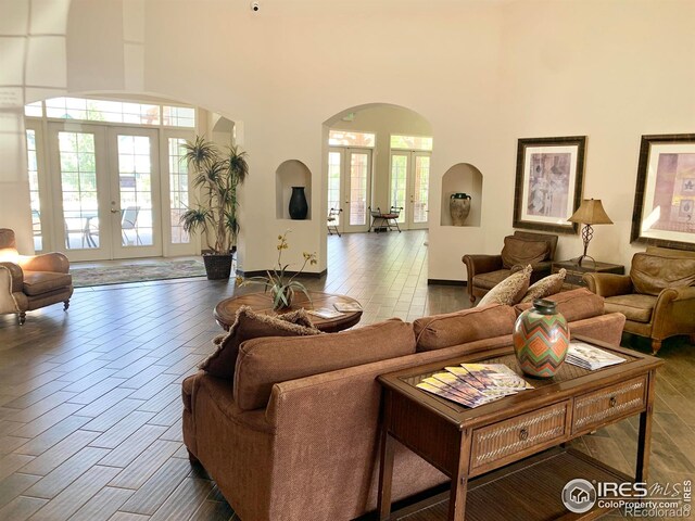 living room featuring a healthy amount of sunlight, a high ceiling, hardwood / wood-style floors, and french doors