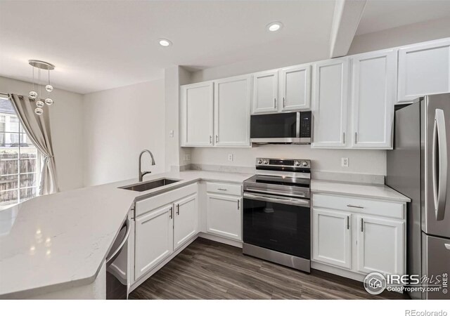 kitchen with stainless steel appliances, sink, kitchen peninsula, and white cabinetry