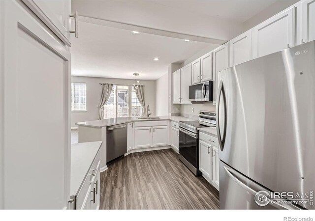 kitchen with light hardwood / wood-style floors, white cabinets, kitchen peninsula, stainless steel appliances, and sink