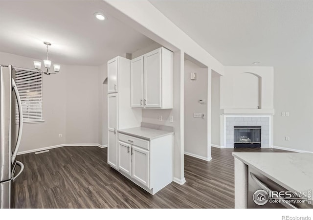 kitchen with an inviting chandelier, white cabinets, dark wood-type flooring, and stainless steel fridge