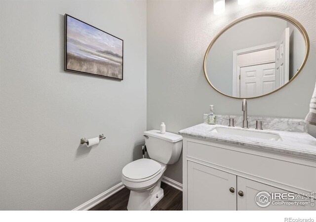 bathroom featuring wood-type flooring, vanity, and toilet