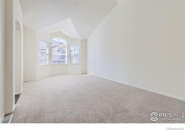 spare room featuring vaulted ceiling and light colored carpet