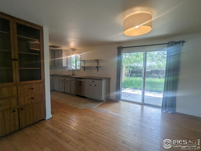 kitchen featuring light wood-type flooring, sink, stainless steel dishwasher, and white cabinets