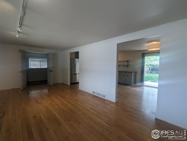 empty room featuring hardwood / wood-style flooring, a textured ceiling, and rail lighting