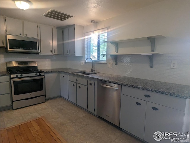 kitchen with gray cabinets, backsplash, decorative light fixtures, sink, and appliances with stainless steel finishes