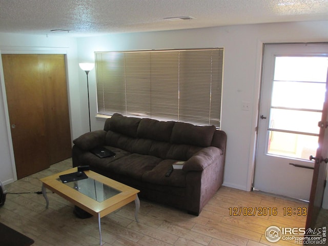 living room featuring a textured ceiling and light wood-type flooring