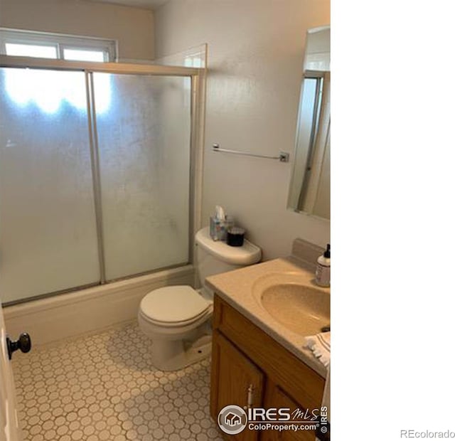 full bathroom featuring vanity, toilet, and bath / shower combo with glass door