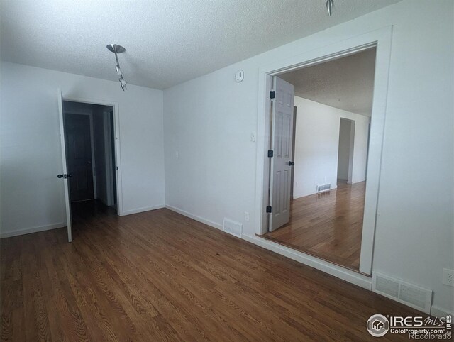 spare room featuring dark hardwood / wood-style flooring and a textured ceiling