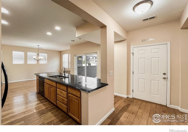 kitchen with pendant lighting, dishwasher, sink, a chandelier, and light wood-type flooring