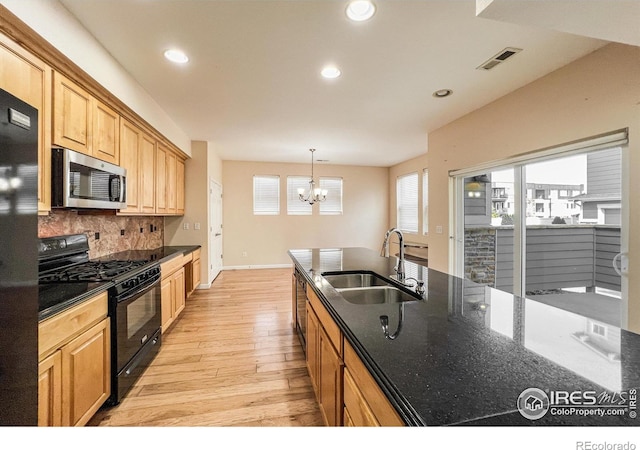 kitchen with black appliances, a chandelier, a wealth of natural light, and sink