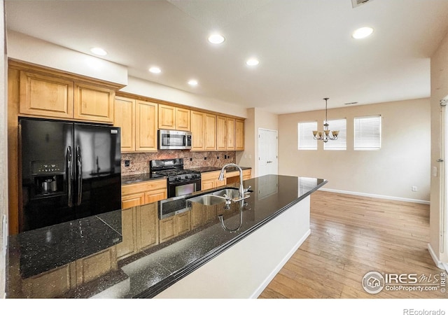 kitchen with hanging light fixtures, light wood-type flooring, a chandelier, sink, and black appliances