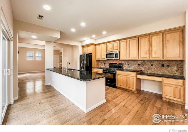 kitchen with light wood-type flooring, sink, black appliances, kitchen peninsula, and decorative backsplash