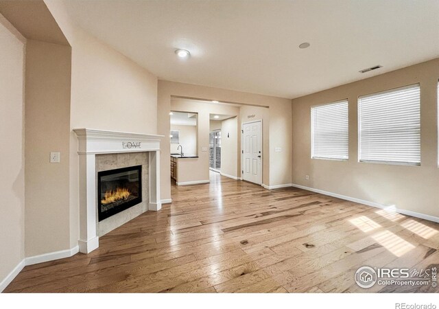 unfurnished living room featuring a tiled fireplace, hardwood / wood-style flooring, and sink