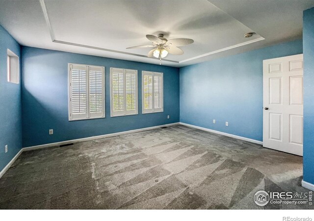 carpeted empty room with a tray ceiling and ceiling fan