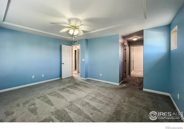 spare room with ceiling fan and dark colored carpet