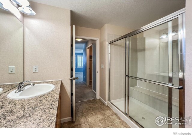 bathroom with a textured ceiling, vanity, and an enclosed shower