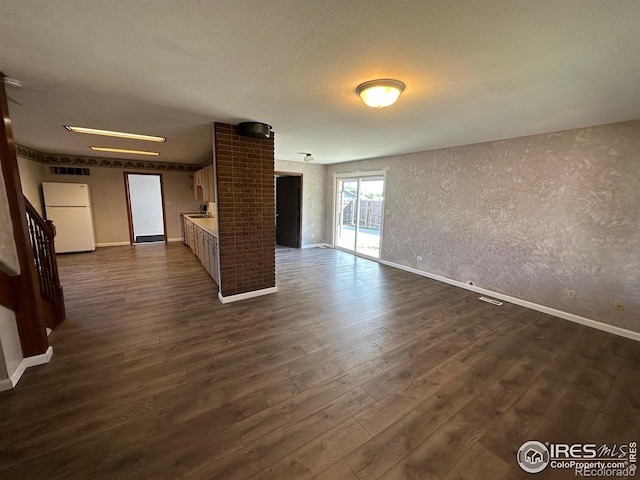 601 E 2nd St, Akron, CO 80720 - unfurnished living room with dark wood-style floors, visible vents, a textured ceiling, and baseboards