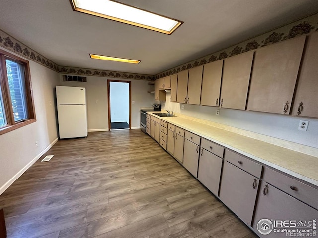 kitchen featuring stainless steel range with electric stovetop, white refrigerator, sink, and light hardwood / wood-style flooring