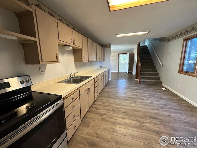 kitchen featuring light hardwood / wood-style flooring, sink, stainless steel electric range, and cream cabinetry