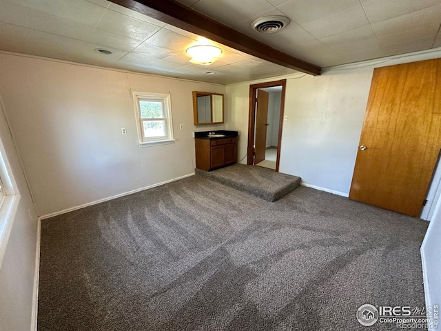 unfurnished bedroom with beamed ceiling and carpet flooring