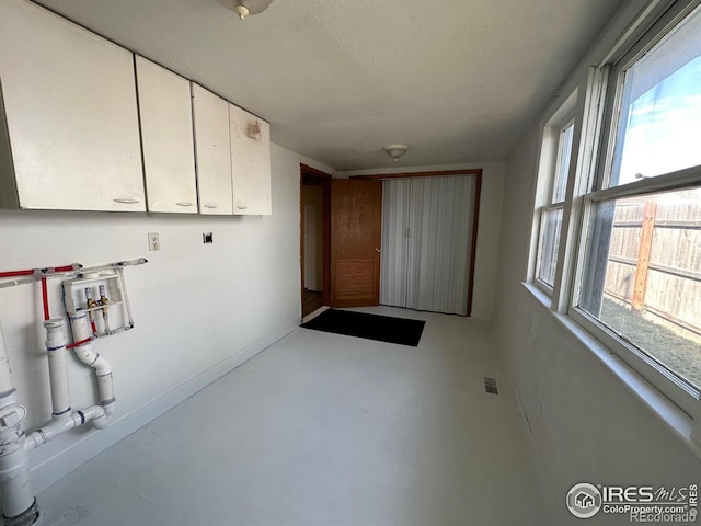 laundry room featuring hookup for a washing machine, plenty of natural light, cabinets, and a textured ceiling