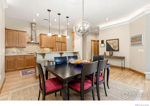 dining room with light wood-type flooring, crown molding, and an inviting chandelier