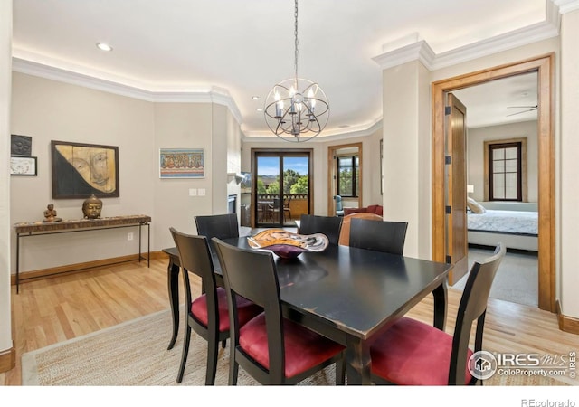 dining area with light wood-type flooring, a notable chandelier, and ornamental molding